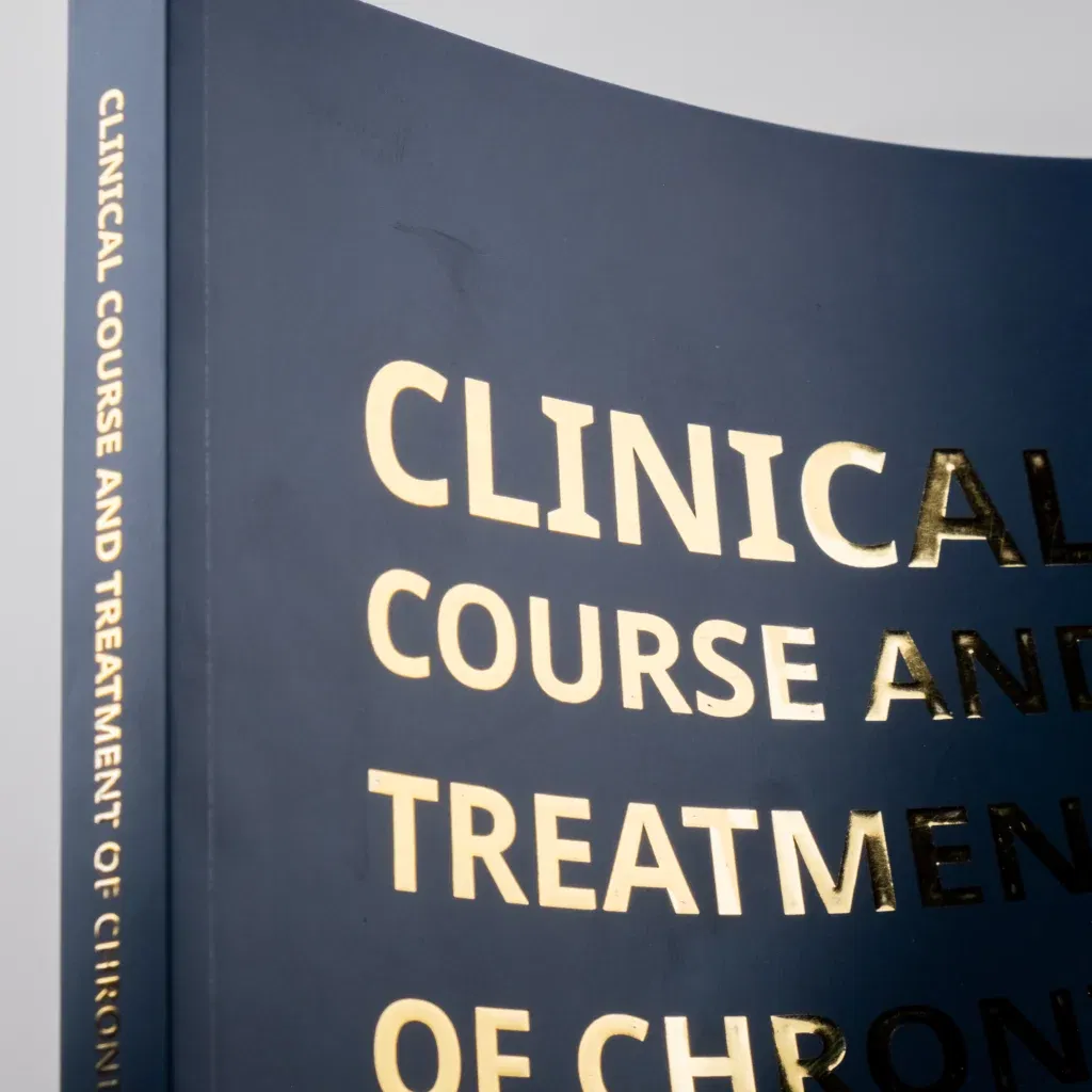 Softcover boek met goudkleurige foliedruk op een donkerblauwe kaft, titel: “Clinical Course and Treatment of Chronic…”.