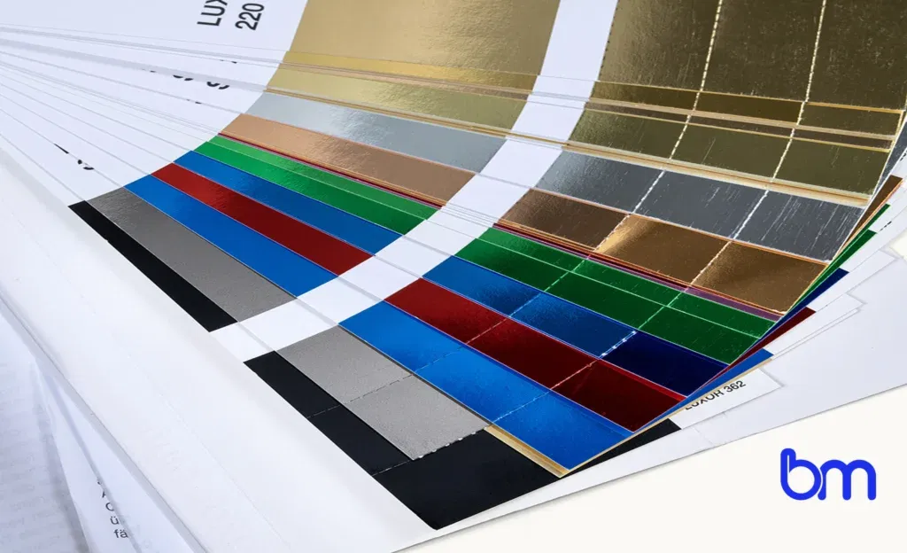 Stalenwaaier met luxe foliedruk in goud, zilver, rood, blauw, groen en zwart, voorbeeld van premium boekafwerking met Boekenmakers-logo rechtsonder.