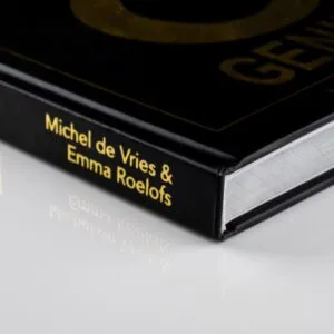 Close-up van zwart hardcover boek met goudopdruk van auteur Michel de Vries & Emma Roelofs.