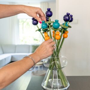 Houten boeket met groene stelen en donker paarsblauwe, petrol en mandarijnkleurige houten bloemen