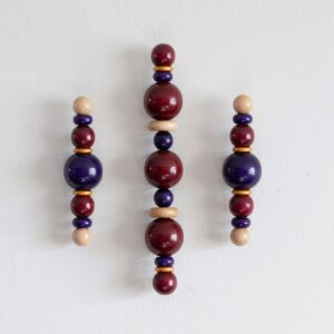 Houten wandsculptuur Burgundy Trio, drie totems in burgundy, donkerblauw en goud aan de muur